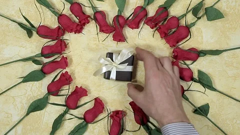 Man's hand puts in the middle of the heart of flowers lined gift box Stock Footage 102274789