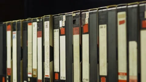 A man's hand puts in place one of the videotapes on the shelf Stock Footage 162854320