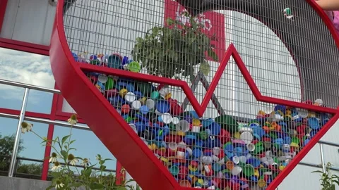 A man's hand puts plastic bottle caps into a Heart shaped recycling bin Stock Footage 211306682