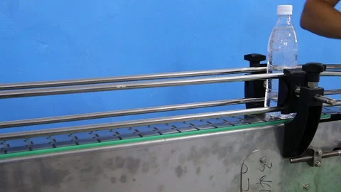 A man's hand puts plastic bottles with carbonated water on the conveyor belt. Video stock 128304679