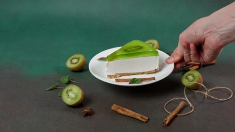 Man's Hand Puts up plate with Slice of Cheesecake with Kiwi Stock Footage 236412918