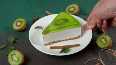 Man's Hand Puts up plate with Slice of Cheesecake with Kiwi Stock-Footage 236412921