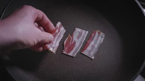A man's hand puts slices of bacon on the pan 動画素材 167183974