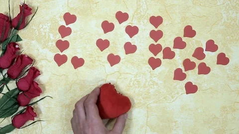Man's hand puts a soft fabric heart near red roses and the inscription love Stock Footage 102274763