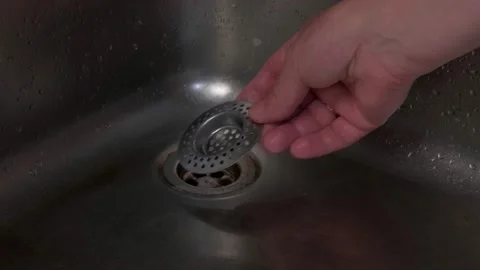 A man's hand puts a strainer in the hole in the iron sink. Stock Footage 150974287
