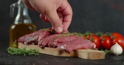 The man's hand puts thyme on pieces of raw beef. Stock Footage 139150193