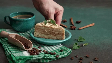 Man's Hand Puts up turquoise plate of Cake Napoleon on a Green Background Stock Footage 235896075