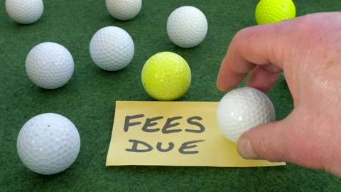Mans hand putting down a Fees Due note among golf balls. Video stock 151378083