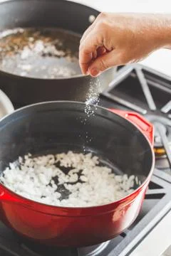 Man's hand putting salt while cooking white onion Stock-Fotos
