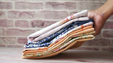 Man's hand putting stack of clothes on table . Stock Footage 156033592