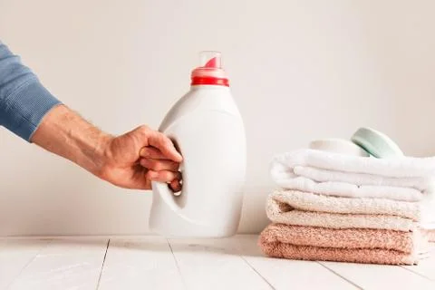 Man's hand putting on the table a jar of gel for washing clothes. Against the Stock Photos