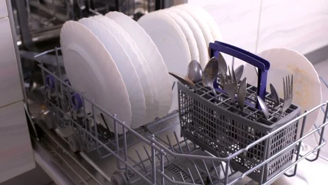 Man's hand is putting white plates and closing dishwasher with dirty white Stock Footage 117825271