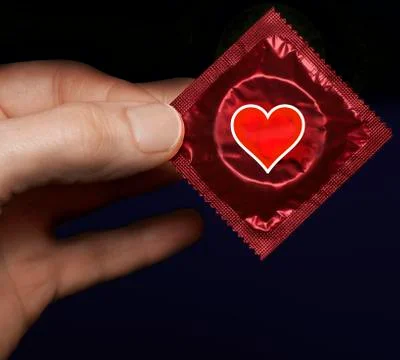 Man's hand with a red condom pack and heart symbol on it Stock Photos