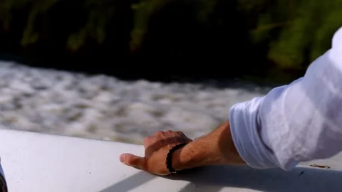 A man's hand rests on the side of a speedboat yacht. The boat is sailing fast on Stock Footage 253773918
