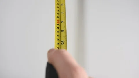 Mans hand retracting a work yellow tape measure against a white background  Stock Footage 88507642