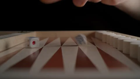 A man's hand rolls the dice to start a game of backgammon. Stock Footage 262999616