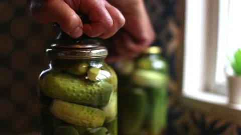 A mans hand rolls up a jar of cucumbers preserves. Stock-Footage 158148472