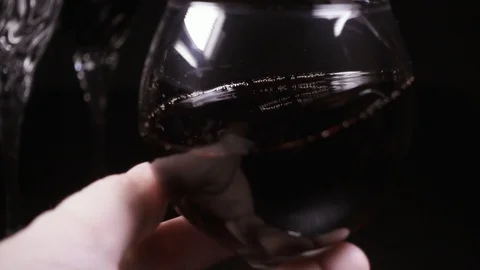 Man's hand rotates a glass of wine slow mo Stock Footage 87404053