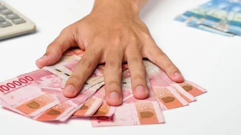 Man's hand on a rupiah note. with a calculator on a white background Stock Photos