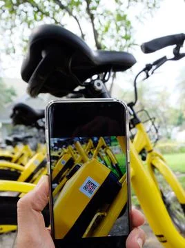 Man's hand scanning a QR code using smart phone to unlock bike,Modern smart p Stock Photos