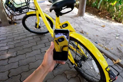 Man's hand scanning a QR code using smart phone to unlock bike,Modern smart p Stock Photos