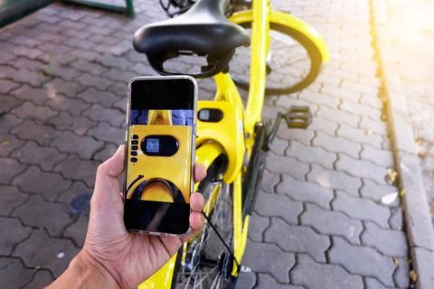 Man's hand scanning a QR code using smart phone to unlock bike,Modern smart p Stock Photos