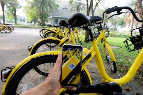Man's hand scanning a QR code using smart phone to unlock bike,Modern smart p Stock Photos