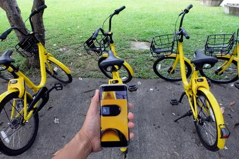 Man's hand scanning a QR code using smart phone to unlock bike,Modern smart p Stock Photos