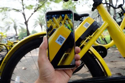 Man's hand scanning a QR code using smart phone to unlock bike,Modern smart p Stock Photos