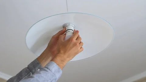 A man's hand is screwing an light bulb into a chandelier in the kitchen Stock Footage 112876189