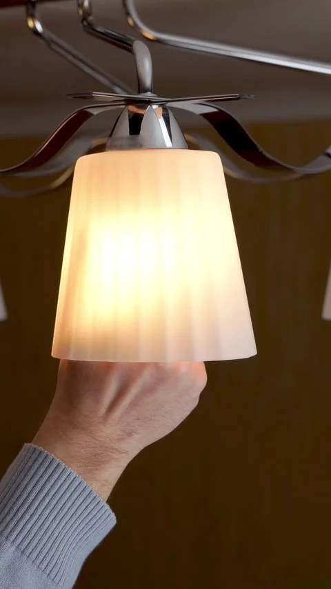 A man's hand is screwing a light bulb into a chandelier Stock Footage 327369955
