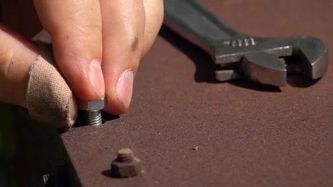 Man’s hand, screwing nut on wind stick on old rusty metal background. Stock Footage 97581866