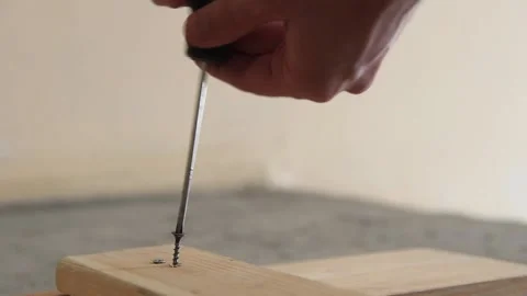 A man's hand is screwing a self-tapping screw into a board with a screwdriver Stock Footage 169798106