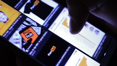 Man's hand scrolling PornHub pornography images on his phone. xxx erotic porn Stock Footage