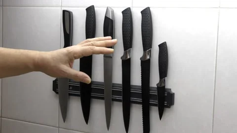 The man's hand selects the desired item from a set of knives on a magnetic strip Stock Footage 149144597