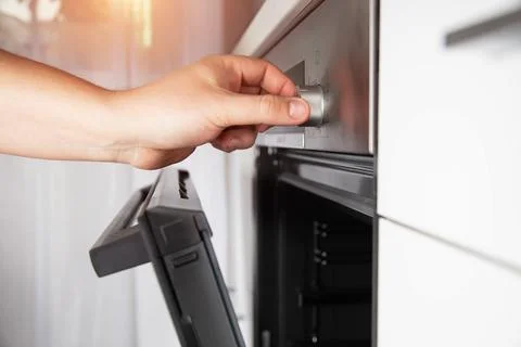 A man's hand selects a function in a modern electric oven and sets the child 스톡 사진