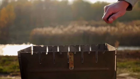 A man's hand sets fire to charcoal in a barbecue. Slowmotion Stock Footage 128373838
