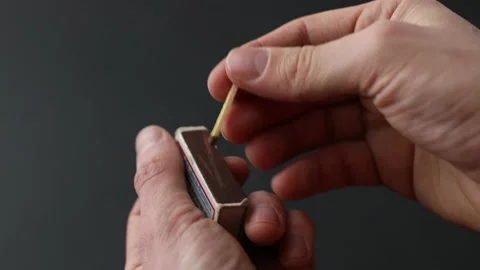 Man's hand sets fire to a match from a box Stock Footage 145536998