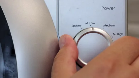A Man's Hand Sets The Microwave Oven. The Hand Turns The Knob From Low To M.Low. Video stock 250333083