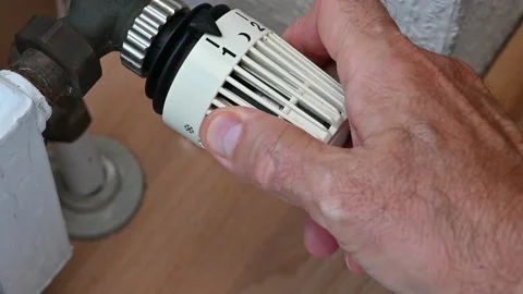 A man's hand sets the thermostat of the heating system to a high temperature. He Stockbeeldmateriaal 219536164