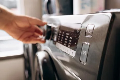 A man's hand sets a washing program. Start washing. Hand adjusting settings.. Stock Photos