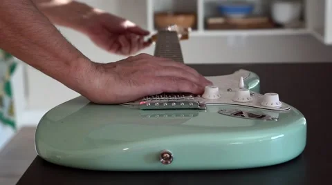Man's hand setting up a green electric guitar   Stock Footage 44829383