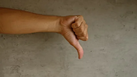 Man's hand showing thumb down gesture against a concrete wall, expressing d.. Stock Footage 289702957