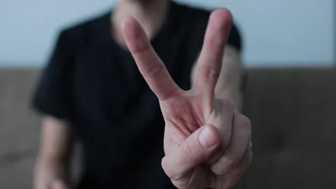 Man's hand is shown in the foreground, making a peace sign with two fingers. Stock Footage 327158373