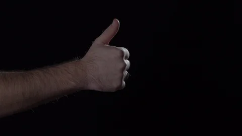 Man's hand shows thumb up gesture on black background. Video stock 124846649