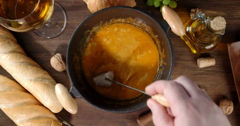 The man's hand a slice of bread mixes fondue in a saucepan. Stock Footage 129142081