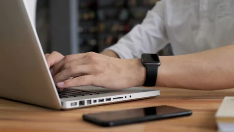 Man's hand with smart watch close up type at desktop keyboard in workspace. Youn Stock Footage 199491462