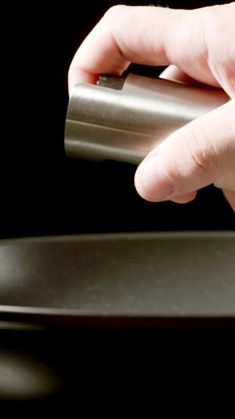 Man's hand sprays vegetable oil from dispenser on a black frying pan on stove Video stock 341793281