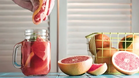 Man's hand squeezes juice from grapefruit into mason jar, slow motion. Stock Footage 87348863