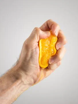 Man's Hand Squeezing Orange Half Stock Photos